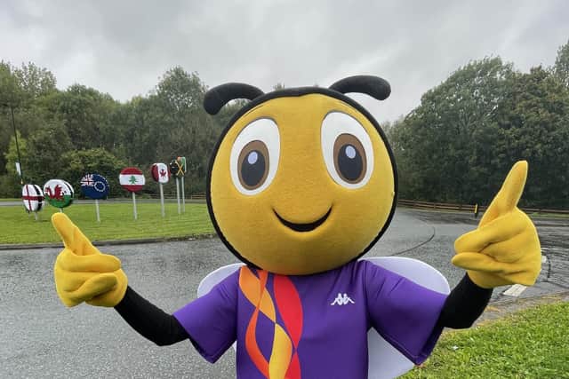 RLWC2021 mascot RugBee next to a floral installation on the roundabout outside Leigh Sports Village