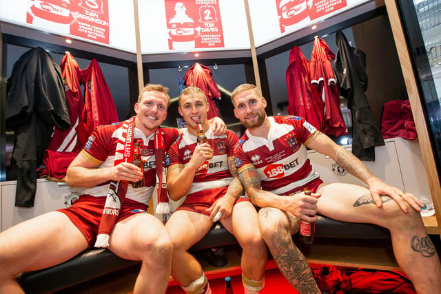 Powell celebrates with Dan Sarginson and Sam Tomkins after the 2018 Grand Final win.