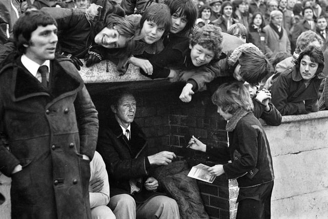 Sheffield Wednesday manager Jack Charlton signs autographs in the dugout before his Division 3 team took on Wigan Athletic in the FA Cup 2nd round match at Springfield Park on Saturday 17th of December 1977. Latics won the game 1-0 with a goal from Maurice Whittle.