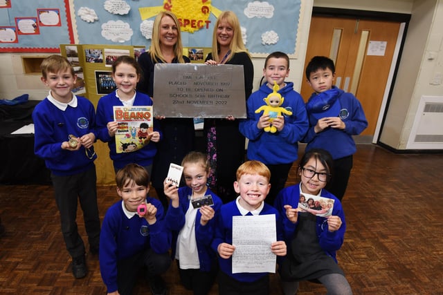 Staff and pupils with some of the items from the time capsule, with a cassette tape of The Spice Girls, Tamagotchi (handheld digital pet popular in 1997), school work, letters and newspapers from the day.