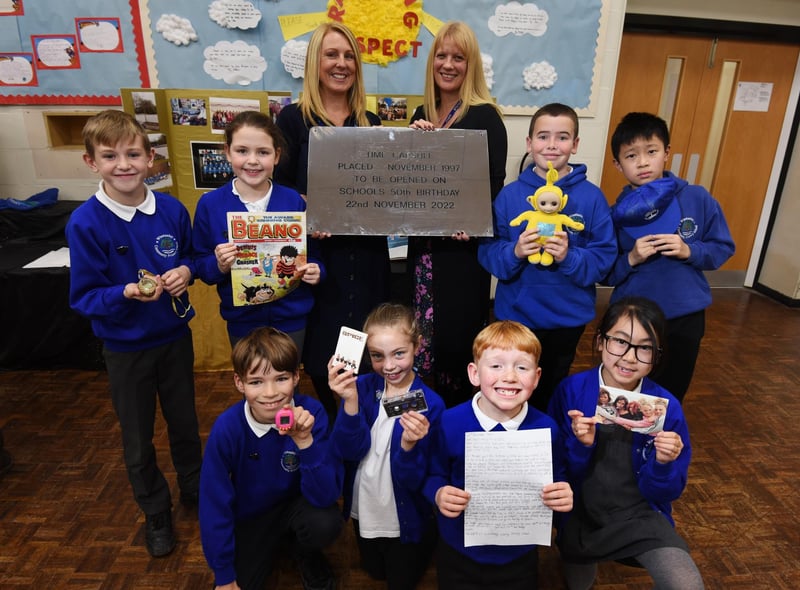 Staff and pupils with some of the items from the time capsule, with a cassette tape of The Spice Girls, Tamagotchi (handheld digital pet popular in 1997), school work, letters and newspapers from the day.
