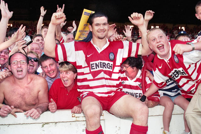 Andy Farrell sits on the wall to celebrate with fans after the match.