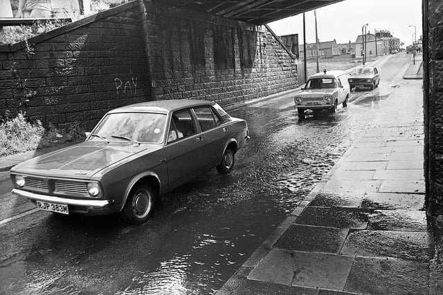 A flooded section of road under the railway bridge on Warrington Road, Lower Ince, in the summer of 1975. In the background is Britannia Bridge Primary School. 