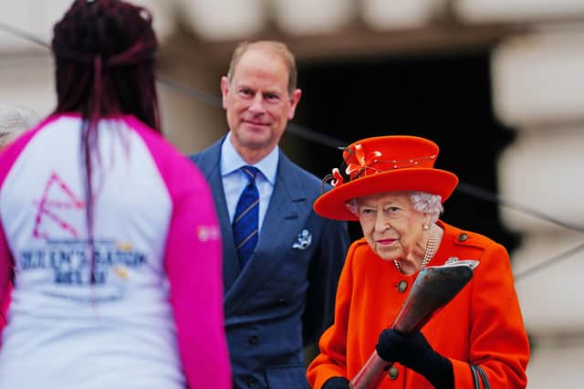 LONDON, ENGLAND - OCTOBER 07: Queen Elizabeth II passes her baton to the baton bearer, British parasport athlete Kadeena Cox, as Prince Edward, Earl of Wessex looks on during the launch of the Queen's Baton Relay for Birmingham 2022, the XXII Commonwealth Games at Buckingham Palace on October 7, 2021 in London, England. The Queen and The Earl of Wessex are Patron and Vice-Patron of the Commonwealth Games Federation respectively. (Photo by Victoria Jones - WPA Pool/Getty Images)