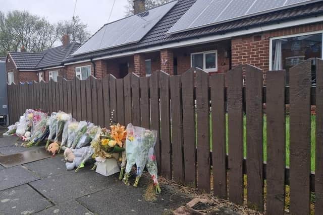 Flowers and toys create a shrine outside the bungalow on Marsh Green