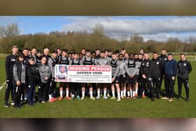 Wigan Athletic players and staff unfurl a banner appealing for help in finding devoted fan Darren Orme