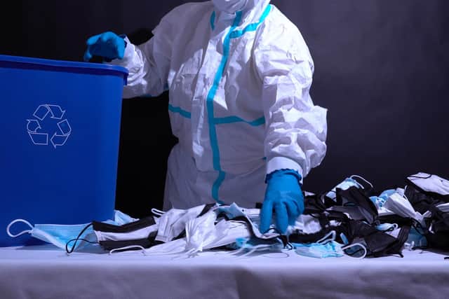 Recycle worker in gloves, sorting medical masks in the recycle bin. Depiction of recycle plant facility. Pollution by surgical masks in coronavirus pandemic and harm to environment. Disposable masks.