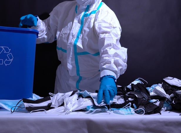 Recycle worker in gloves, sorting medical masks in the recycle bin. Depiction of recycle plant facility. Pollution by surgical masks in coronavirus pandemic and harm to environment. Disposable masks.