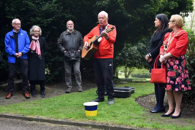 Musician Lawrence Hoy performing to close last year's Workers' Memorial Day ceremony around the memorial tree and plaque in Mesnes Park, Wigan.