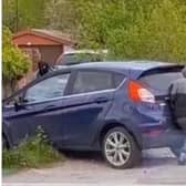Two of the gang members try to shove their getaway car after it became wedged on a retaining wall off Lily Lane, Bamfurlong. Moments earlier they had knocked a young man off his e-bike in an attempt to rob him