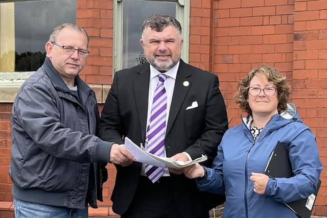 Coun Steven Evans, centre, receives the petition from Michael Winstanley and Angela Stockley