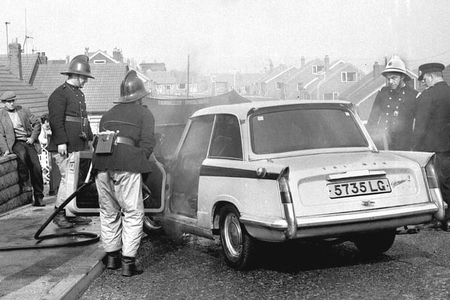 Wigan firemen deal with a fire in the engine of a Triumph Herald Vitesse in Aspull in 1969.