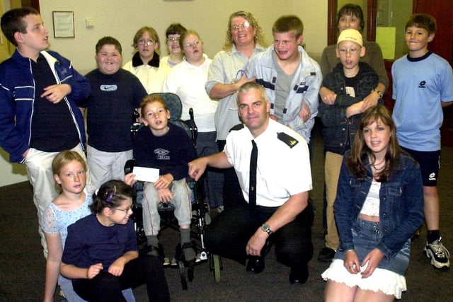 Community Police Officer Shaun Fairhurst presents  Wigan  Mencap  Summer  Funclub with a cheque for £100 from the G M  Police  Charity  Fund.Andrew Featherstone ( centre) receives the cheque on behalf of the group. 