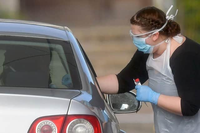 A worker in PPE including gloves, a face mask, eye protection and an apron, swabs an NHS worker at a drive-in facility to set up to test for the novel coronavirus COVID-19, in the car park of Chessington World of Adventures (Photo: BEN STANSALL/AFP via Getty Images)