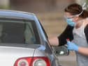 A worker in PPE including gloves, a face mask, eye protection and an apron, swabs an NHS worker at a drive-in facility to set up to test for the novel coronavirus COVID-19, in the car park of Chessington World of Adventures (Photo: BEN STANSALL/AFP via Getty Images)