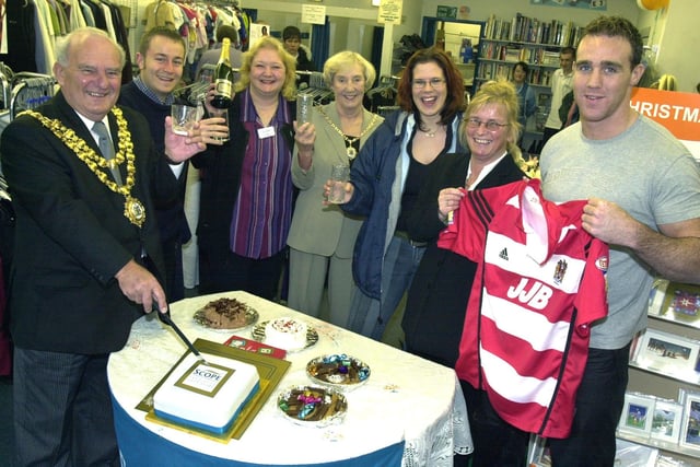 The Mayor of Wigan, Coun. Geoff Roberts, cuts the cake to celebrate the 50th birthday of Scope at the Wigan shop with Manager, Jackie Shambley, the mayoress, Mrs. Betty Roberts, Assistant Manager, Sandra Ackers, Wish FM presenters, Matt McCann and Emma Simmons and Wigan RL star, Paul Johnson, who presented the shop with his playing shirt.