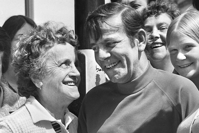 Norman Wisdom happy to sign autographs and joke with fans in Wigan town centre in 1975.