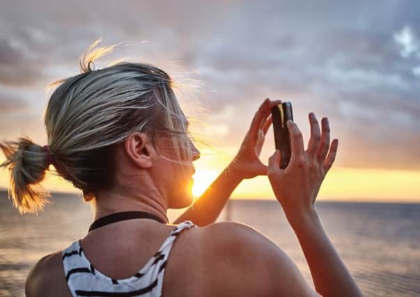 Female photographer taking pictures on peer sunset, lowlight, solar flare, sun flare, head and shoulders, wind blowing hair, dramatic scene