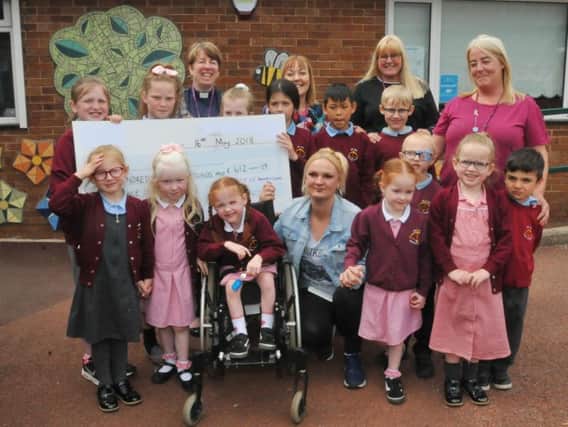 Staff and pupils hand over a cheque for Skye McCombs to mum Nicola Kirkpatrick, pictured with sister Summer