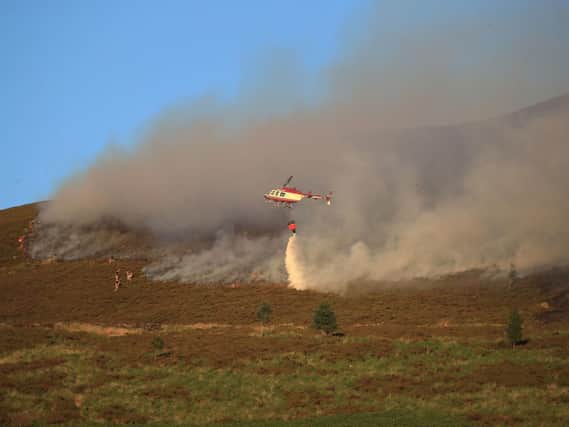 A helicopter drops water as firefighters tackle the fire