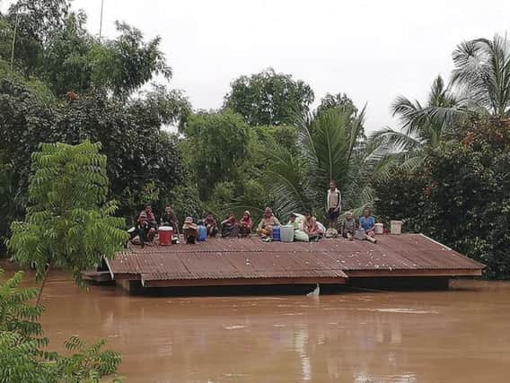 Villagers take refuge on a rooftop above flood waters from a collapsed dam in Laos. See letter about foreign aid
							           Picture: Attapeu Today via AP