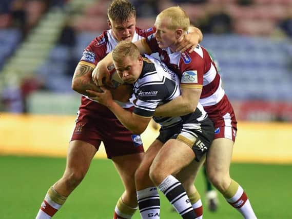 Hull FC's Danny Washbrook  is tackled by Wigan Warriors' Liam Farrell and Ryan Sutton