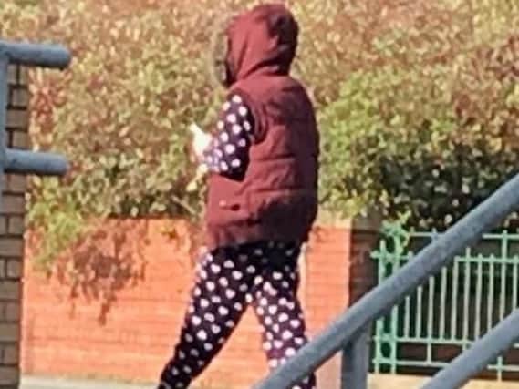 The woman carrying out the scam wears spotted pyjamas and a hooded top