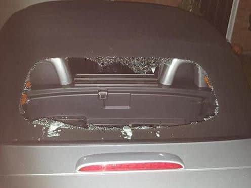 One of the cars with its rear window smashed by the gang