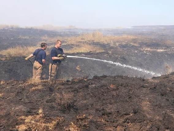 Firefighters damp down after the blaze on Winter Hill