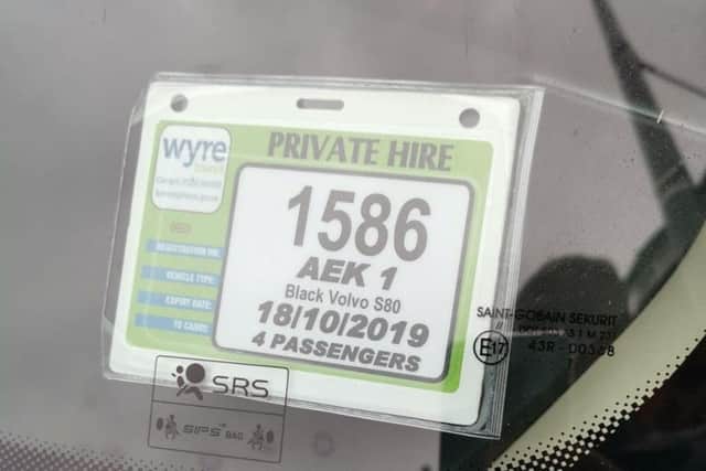 The private hire badge displayed in the front window