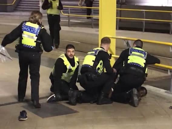 Police restraining a man after he stabbed three people at Victoria Station in Manchester