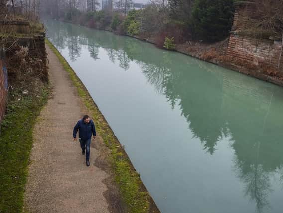 A man walks alongside the Bridgewater Canal in Manchester which has turned a strange shade of blue