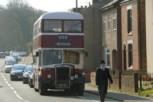 A vintage double decker bus leads the funeral procession along Wigan Road in Standish