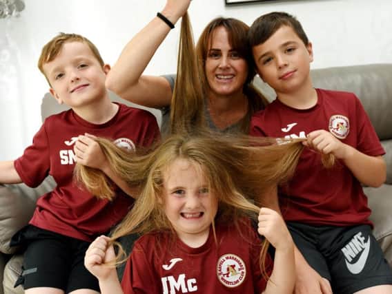 Young Jude McClarnan, five, is going to have is long hair chopped for charity, raising funds for Alder Hey Childrens Hospital and donating his hair to a charity, pictured with proud mum Jodie McClarnan, centre, and brothers, Sonny, seven, left, and Mikey, 10, right.