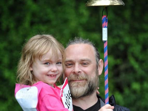 Ellie Rieveley ringing the starter bell at Race For Life with dad Ben