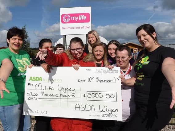 Asda community champions Cheryl Gillan, left, and Charlene Frodsham, right, present a 2,000 cheque to My Life Legacy, pictured with My Life staff and members at Thompson House, Standish