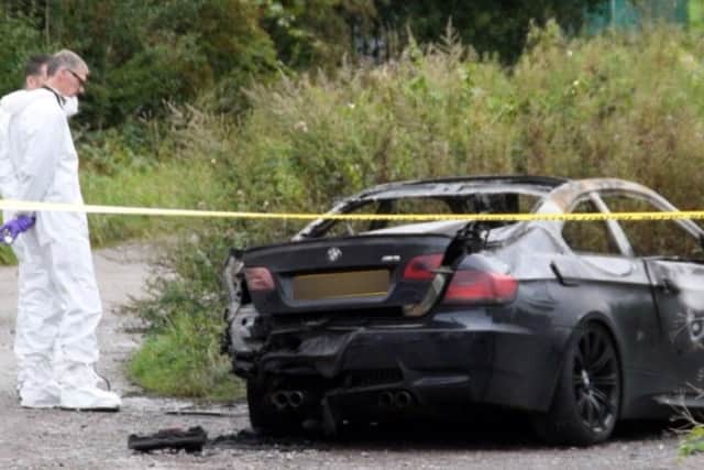 Forensics inspect a destroyed BMW which was found near the scene of the first shooting