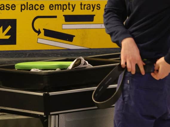 A passenger replacing a belt after having passed through security at Manchester Airports Terminal 1