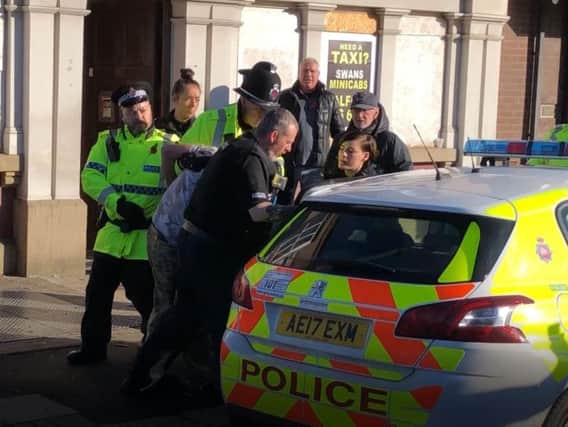 A man is bundled away by police to protect him from the angry after he disrupted a silent tribute with fireworks at a Remembrance Sunday event