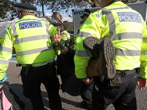 Police officers arrest an activist during a protest, during demonstrations by the climate change action group Extinction Rebellion (Photo by ISABEL INFANTES/AFP via Getty Images)