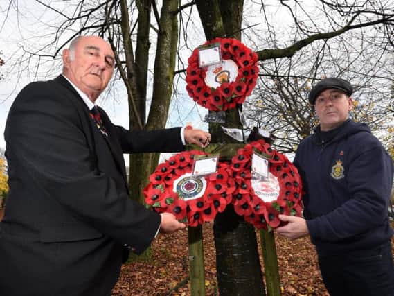 Tom Catterall and Dave Myers, from the Wigan Royal British Legion, replace the poppy wreaths after they were stolen and later found vandalised
