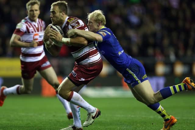 Wigan Warriors Lee Mossop is tackled by Warrington Wolves' Rhys Evans