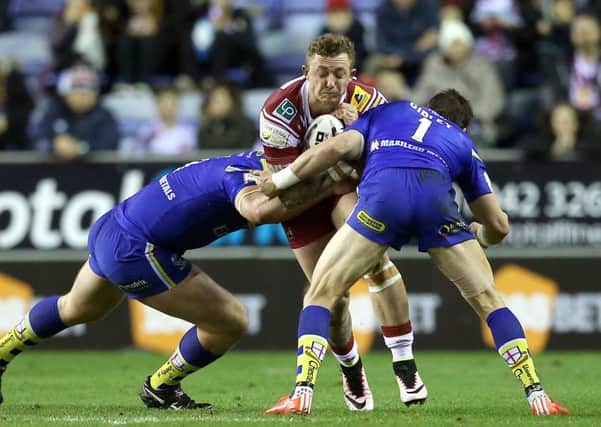 Wigan Warriors Josh Charnley is tackled by Warrington Wolves' Chris Hill (left) and Kurt Gidley (right)