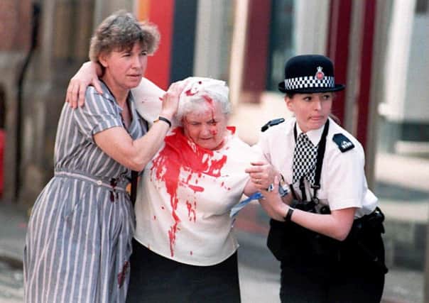 An injured woman being helped away from the scene in Manchester, following the IRA bomb blast which ripped the heart out of  the city's shopping area
