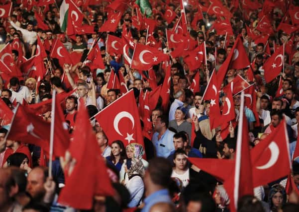 People wave Turkish flags as they gather in Taksim Square in Istanbul