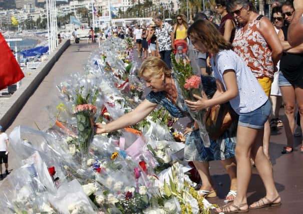 Two women place flowers along the beach of the Promenade des Anglais in Nice, France, following the Bastille Day truck attack