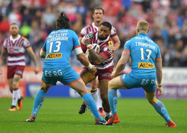 Frank-Paul Nuuausala of Wigan Warriors is tackled by St Helens' Louie McCarthy-Scarsbrook