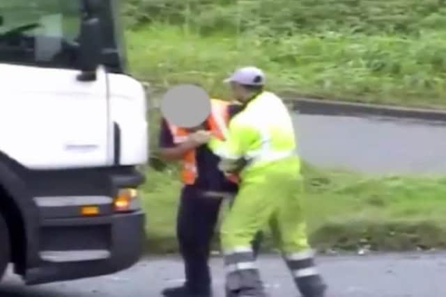 The man in the green overalls attacks the driver of the lorry