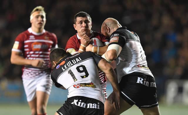 Ben Flower is tackled by Widnes forwards Macgraff Leuluai and former Wigan team-mate Gil Dudson