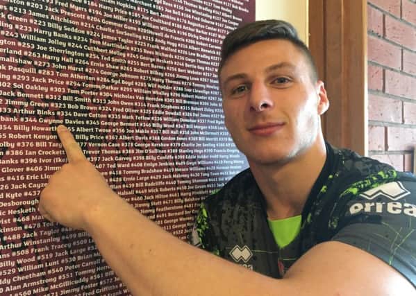Tom Davies points to his great-grandad's name on the list of Wigan's heritage numbers